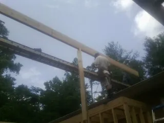 Carpenter setting a ridge beam over a new addition frame — Ice Dam Removal by Roofing Brothers in Heathsville