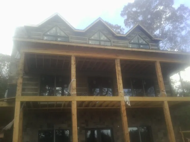 Dormers and porch framing on a large log home under construction — Roof Coating work by our crew in Heathsville