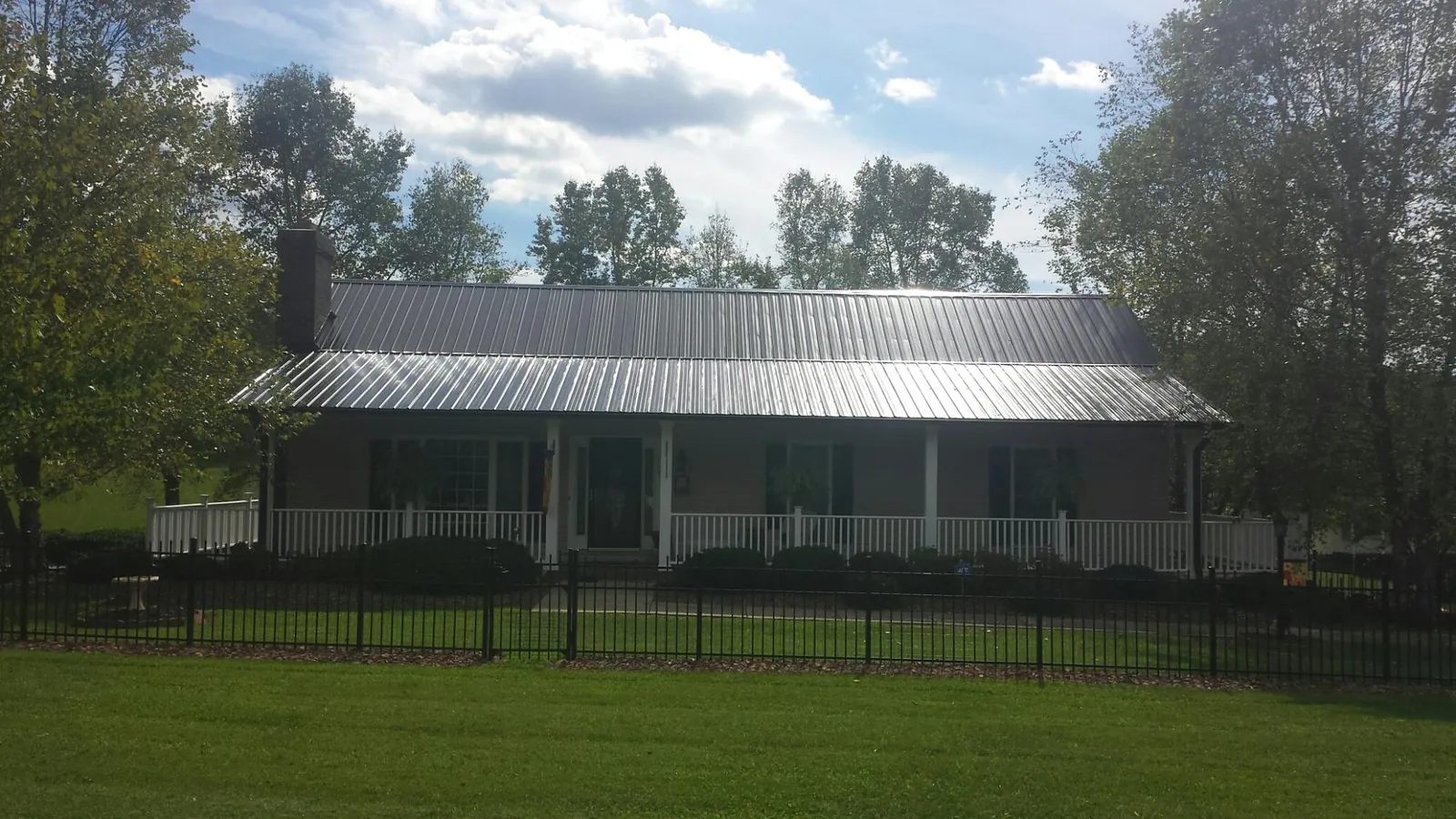 Gray metal roof on a brick ranch with a full width front porch — Gutter Guard Installation work by our crew in Heathsville