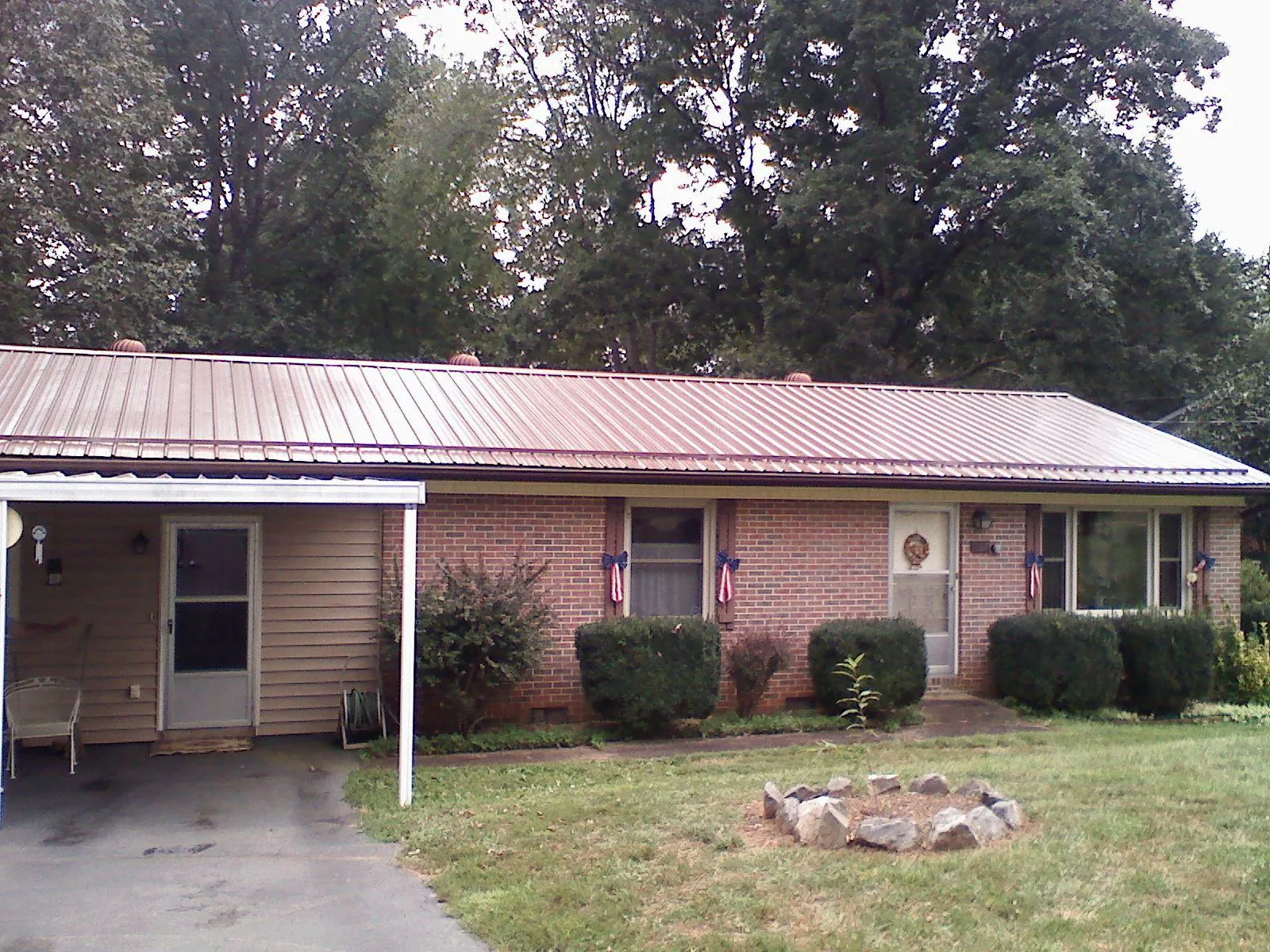 Bronze metal roof and carport on a brick ranch home — Roof Repair work by our crew in Heathsville
