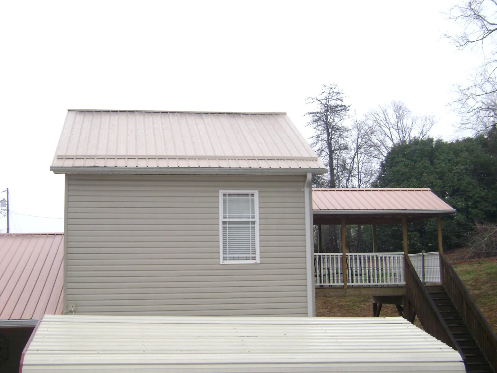 Tan metal roofs on a two story addition and attached porch, from a Roof Replacement job in Heathsville