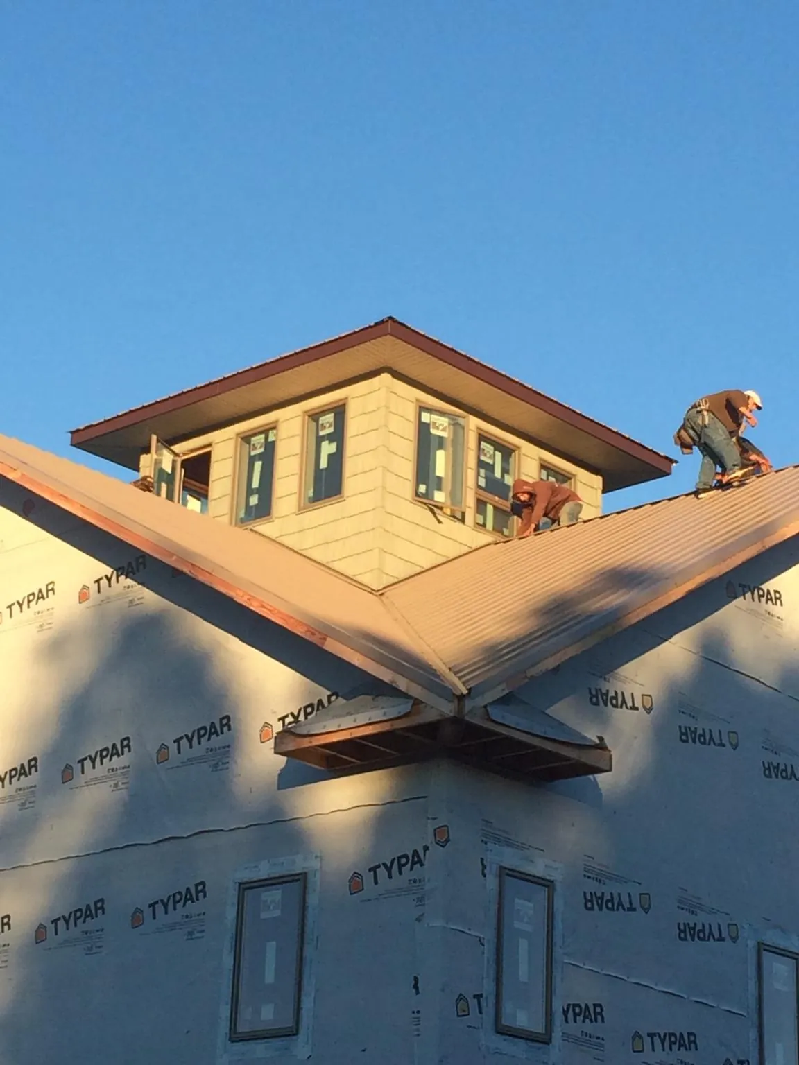 Roofers working around a rooftop cupola on a new metal roof at sunset — Roof Waterproofing in Heathsville by Roofing Brothers